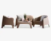 Et moderne udendørs loungesæt i en neutral beige farve, bestående af to armlæn-stole og en to-personers sofa med glatte, afrundede kanter. Sættet inkluderer et matchende lavt bord, der er pyntet med en bakke med vinglas, en vinflaske, snacks og en dekorativ plante. Sæderne er udstyret med bløde, teksturerede pyntepuder i lyse og afdæmpede nuancer for ekstra komfort.