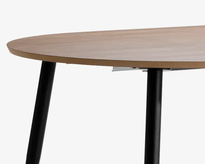 Rund bordplade med en glat, lys træfinish og en slank profil. Understøttet af skrå, cylindriske ben i sort metal, hvilket giver et moderne og minimalistisk udtryk. Bordpladens kant er let affaset for et elegant udseende.
