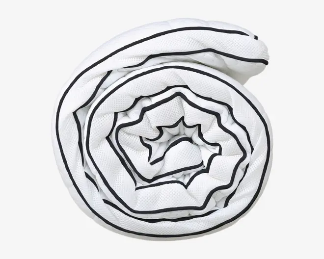 Et sammenrullet hvidt tekstil med en struktureret overflade og sort kantbånd langs kanterne. Materialet ser blødt og let ud, og den sorte kant danner et spiralformet mønster, når produktet er rullet stramt sammen.