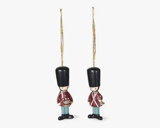 Par små hængende gardefigurer med guldsnor, sorte høje hatte, røde frakker, lyseblå bukser og sorte sko.