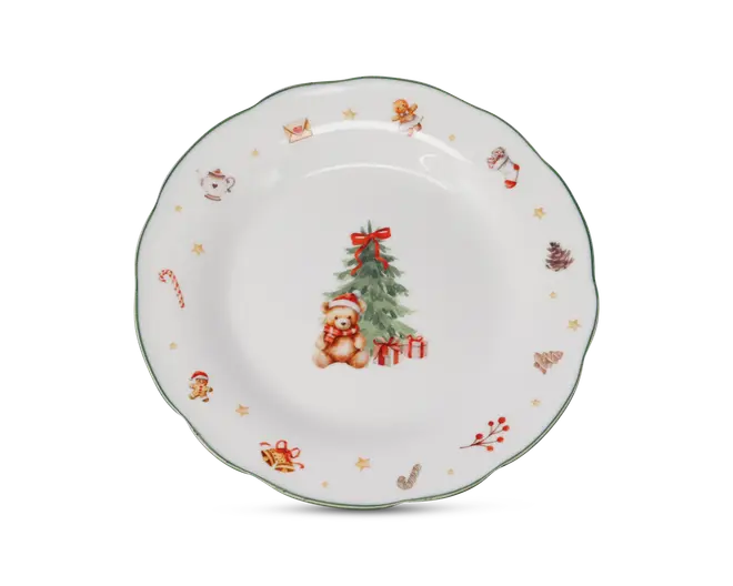 Rund porcelænstallerken med et festligt julemotiv. Midten viser en bamse med nissehue, der sidder foran et pyntet juletræ med rød sløjfe og flere indpakkede gaver. Tallerkenens kant er dekoreret med små illustrationer som en sukkerstok, honningkagemand, julesok, kogler, kristtorn, tekande og stjerner. Tallerkenens rand har en diskret grøn kant.