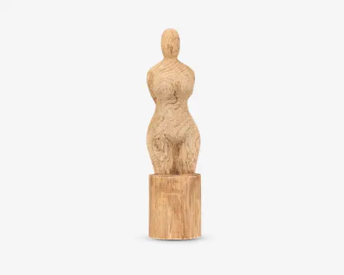 Håndskåret træfigur med en rund, abstrakt menneskelig form, der har fremhævede kurver og teksturerede overfladedetaljer. Figuren står på en cylindrisk træfod, hvor træets årer og naturlige farvevariationer er synlige. Udskæringen har et rustikt udtryk og fremhæver organiske former.