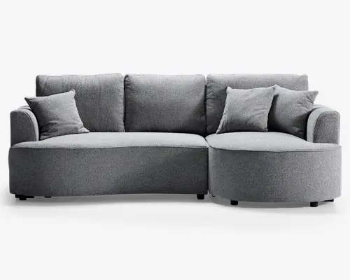 Moderne grå sofa med blødt stofbetræk, der har en unik afrundet chaiselong på højre side. Sofaen har tre store ryghynder og tre matchende pyntepuder for ekstra komfort. Armlænene er let buede, og designet er elegant og nutidigt, hvilket gør den velegnet til en stilfuld stue.
