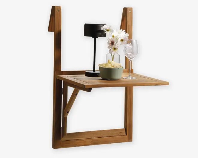 Kompakt, vægmonteret bord i træ med sammenklappeligt design. Bordpladen er rektangulær med lameller og understøttes af solide sidebeslag. På bordet står en sort, moderne lampe, en lille hvid vase med kunstige hvide blomster, et klart vinglas og en grøn skål med chips. Træet har en naturlig finish, der fremhæver årerne og den varme tone.