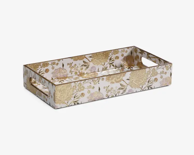 Rektangulær bakke med høje sider og udskårne håndtag i begge ender. Overfladen har et elegant blomsterdesign i guld og bløde pastelfarver på en hvid baggrund, hvilket giver et luksuriøst og dekorativt udtryk. Bakken har en blank finish, der fremhæver de metalliske detaljer og gør den velegnet til servering eller dekoration.