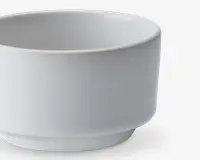 En lille, rund, hvid keramikskål med en glat, mat overflade. Skålen har lige sider og en let hævet bund, hvilket giver den et moderne og minimalistisk udtryk. Kanten er let buet, og designet er enkelt uden dekorationer.