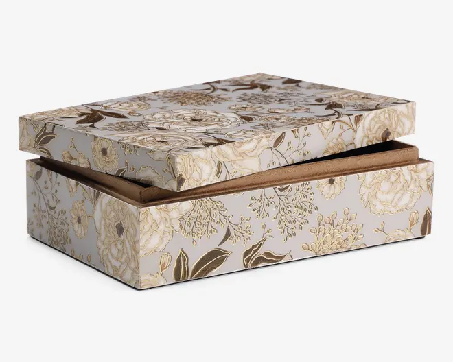 Rektangulær æske med delvist åben låg, dekoreret med et elegant blomstermønster i nuancer af beige, creme og brun på en lys baggrund. Æsken har en solid konstruktion og en glat, mat overflade. Indersiden er foret med et blødt, brunt materiale, som giver ekstra beskyttelse til indholdet. Blomstermotivet dækker alle synlige flader og giver æsken et dekorativt og sofistikeret udtryk.