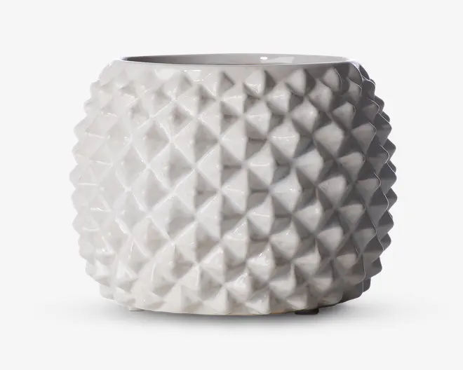 En rund, blank hvid keramisk beholder med en geometrisk, diamantmønstret tekstureret overflade. Ydersiden har hævede, pyramideformede former, der skaber en tredimensionel effekt. Toppen har en bred, glat åbning, og det samlede design er moderne og dekorativt.