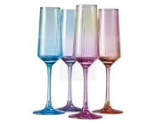 Sæt med fire høje, riflede glas med lodrette riller og en gradueret pastel farve. Hvert glas har sin egen nuance, herunder blå, lilla, pink og rav, hvor farven bliver mere intens mod bunden og stilken. Glassene har et moderne, elegant design med en slank stilk og en bred, stabil fod.