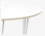 Nærbillede af bordkant med en glat, rund hvid bordplade og en lys trækant. Bordet understøttes af slanke, skråtstillede metalben med blank overflade, hvilket giver et moderne og minimalistisk udtryk.