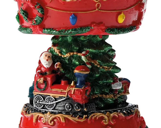 Dekorativ julescene med julemanden, der kører i et rødt legetøjslokomotiv rundt om et grønt træ, malet i klare røde, grønne, gyldne og blå detaljer med guirlande og festlige lys.