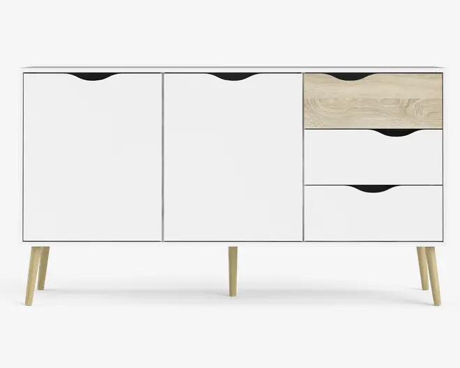 Et moderne skænk med et minimalistisk design, hvid finish og detaljer i naturtræ. Den har to store skabslåger til venstre og tre skuffer til højre, hvor den øverste skuffe har et lyst træmønster. Skuffer og låger har udskårne greb for et stilrent udtryk. Skænken står på fire skrå, lyse træben, hvilket giver et skandinavisk inspireret look.