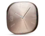 Moderne vægur med afrundet firkantet form og metallisk rosaguld finish. Uret har minimalistiske hvide time-markeringer samt tal ved 12, 3, 6 og 9. De tre slanke visere til timer, minutter og sekunder er i hvid, hvilket giver god læsbarhed.
