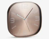 Moderne vægur med afrundet firkantet form og metallisk rosaguld finish. Uret har minimalistiske hvide time-markeringer samt tal ved 12, 3, 6 og 9. De tre slanke visere til timer, minutter og sekunder er i hvid, hvilket giver god læsbarhed.