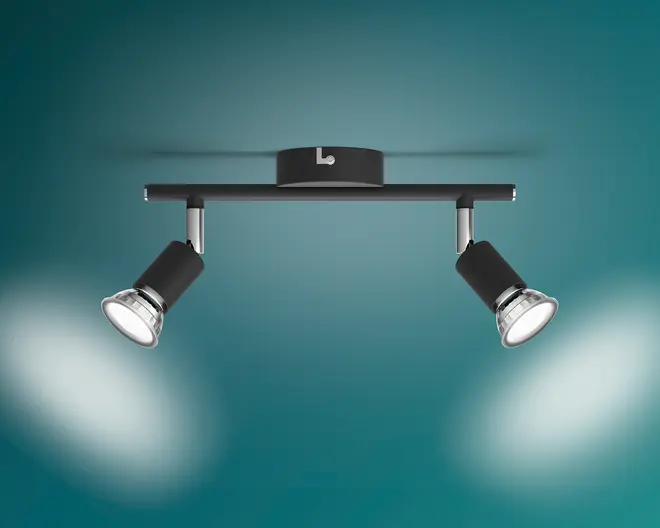 Sort loftmonteret spotlampe med to lyskilder, en slank vandret skinne, rund midterdel og to justerbare, vinklede lampehoveder med sølvdetaljer.