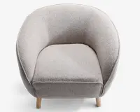 En moderne lænestol med rund ryg og sider, polstret med et lysegråt, tekstureret stof. Sædepuden er tyk og blød, hvilket giver god komfort. Stolen står på fire korte, lyse træben, hvilket giver et moderne og hyggeligt udtryk.