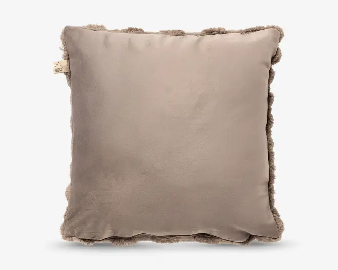 Firkantet pude i taupe med glat, velour-lignende forside og blød, fluffy flæsekant hele vejen rundt; lille stofmærke i venstre side.