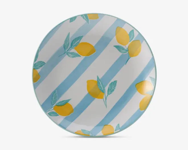 Rund tallerken med et mønster af gule citroner med grønne blade, spredt ud over en baggrund med brede, diagonale lyseblå og hvide striber. Designet er lyst og sommerligt og giver et friskt udtryk.