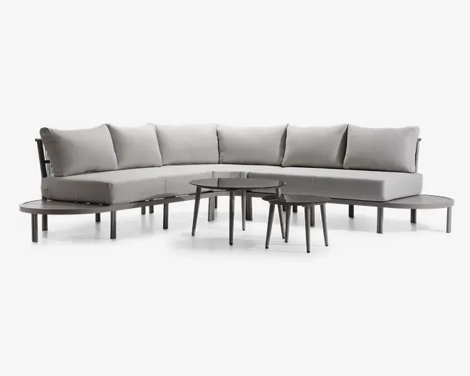 Moderne L-formet sofa med lysegråt betræk, tykke sædehynder og fem store, bløde ryghynder for ekstra komfort. Sofaen har slanke, lige metalben i grå finish, hvilket giver et moderne og let udtryk. Sættet inkluderer to runde, indskudsborde med tynde, skrå ben og mørke bordplader, der matcher det minimalistiske design.