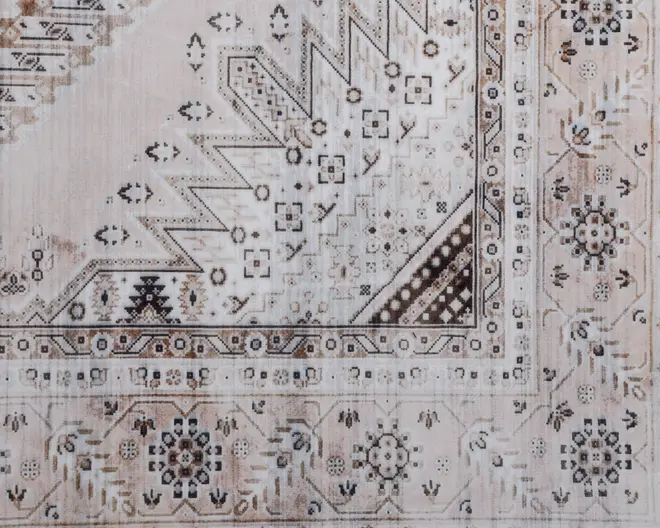 Billedet viser et udsnit af et tæppe med et traditionelt geometrisk og blomsterinspireret mønster. Designet indeholder zigzag-linjer, små firkantede motiver og detaljerede kanter i beige, brun og cremefarvede nuancer. De blomsteragtige elementer er symmetrisk arrangeret, og tæppet har et let slidt look, hvilket giver det et vintage udtryk.