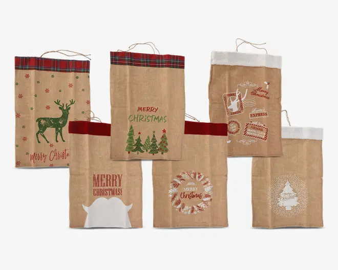 Sæt med seks festlige gaveposer lavet af jute, hver med unikke julemotiver. Poserne har forskellige tryk, herunder en grøn rensdyr med snefnug, juletræer med teksten 'Merry Christmas', julemandens slæde og poststempler, en hvid silhuet af julemandens skæg med 'Merry Christmas!', en krans med 'Merry Christmas' i midten og et stiliseret juletræ med strålende linjer. Nogle poser har ternet eller hvid kant øverst, hvilket giver et ekstra julet udtryk. Designene er trykt i rød, grøn og hvid og giver et rustikt og hyggeligt look.