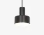 En moderne pendellampe med en mat sort cylindrisk metalskærm. Designet har en bredere nederste del og en smallere øverste del, hvilket giver en trinvist silhuet. Lampen hænger i en sort ledning, og undersiden er åben, så lyset skinner direkte nedad. Overfladen er glat, og stilen er minimalistisk, velegnet til moderne indretning.