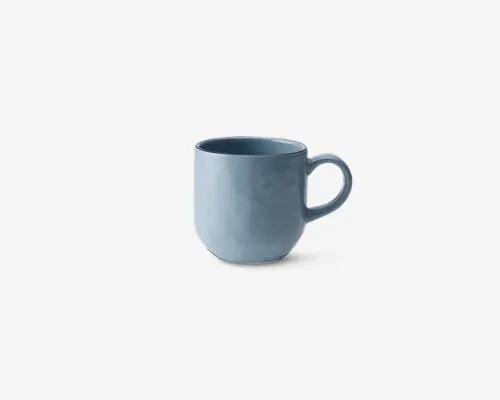 Et keramikkrus med en glat, blank lyseblå overflade. Kruset har en rund form og et stort, behageligt håndtag. Randen er en smule tykkere for ekstra holdbarhed, og det samlede design er enkelt og moderne.