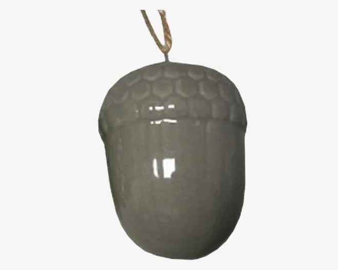 Blank keramisk pynt formet som et agern, med en struktureret top med bikubemønster og en glat underdel. Pynten har en neutral, lysegrå farve og er udstyret med en løkke af naturfarvet snor til ophængning.
