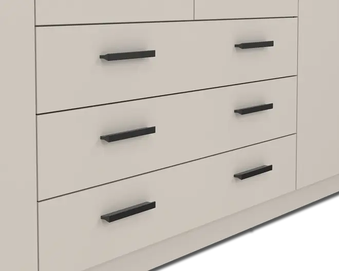Nærbillede af tre store skuffer med en glat, mat lysebeige overflade. Hver skuffe har to lige, horisontale sorte greb med et moderne, minimalistisk design. Grebene er jævnt fordelt og monteret tæt på den øverste kant af hver skuffefront.