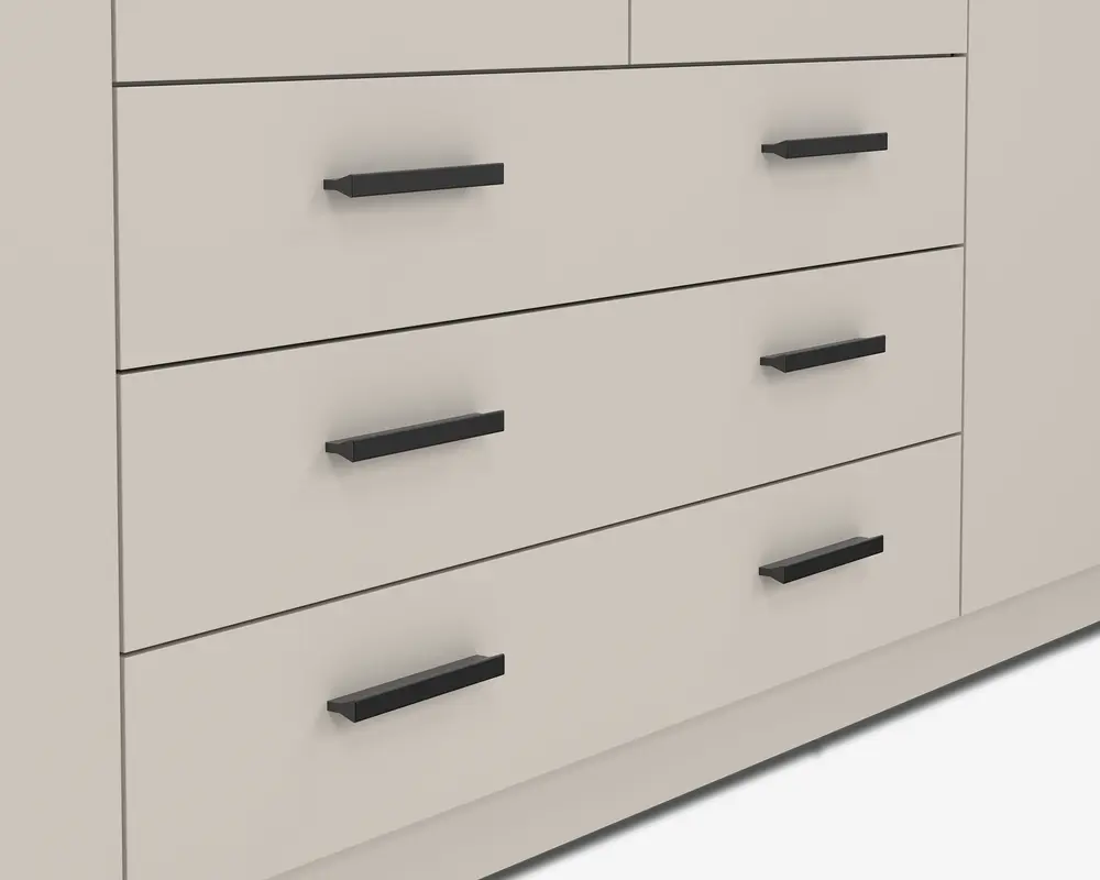 Nærbillede af tre store skuffer med en glat, mat lysebeige overflade. Hver skuffe har to lige, horisontale sorte greb med et moderne, minimalistisk design. Grebene er jævnt fordelt og monteret tæt på den øverste kant af hver skuffefront.