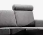 Nærbillede af en moderne sofa sektion betrukket med tekstureret gråt stof. Designet har en høj ryg med en justerbar cylindrisk nakkestøtte for ekstra komfort. Armlænet er bredt og polstret, og sædehynderne er tykke og faste, hvilket giver god siddekomfort. Stoffet har et diskret meleret mønster, der giver et moderne udtryk.