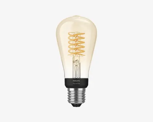 Klar glaspære med synlig spiralformet glødetråd i retrostil, der udsender et varmt, ravfarvet skær. Soklen er af metal med et sort bånd mærket 'PHILIPS Hue white.' Pæren har en standard skruefatning og en dråbeform, velegnet til dekorativ belysning.