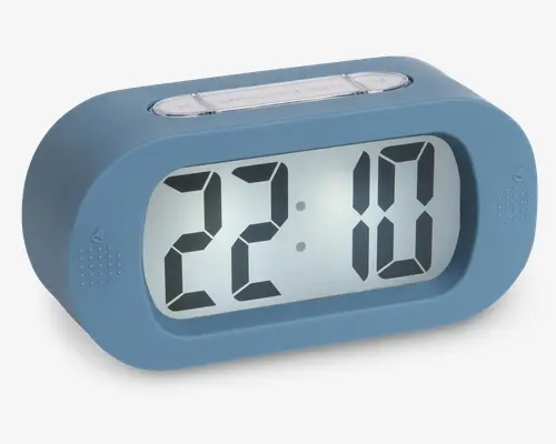 Digitalt ur med stor, letlæselig skærm, der viser tiden i 24-timers format. Uret har en afrundet rektangulær form med et mat blåt kabinet. Der er to små højtaler-lignende mønstre på hver side af displayet og et gennemsigtigt knap-panel på toppen, sandsynligvis til indstilling af tid eller alarm. Designet er moderne og minimalistisk.