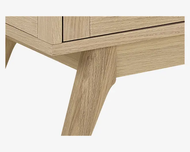 Nærbillede af et møbel med lys egetræsfinish og en glat, naturlig træstruktur. Billedet fremhæver et skråt, tilspidset ben og en enkel, moderne kant, hvilket indikerer en solid konstruktion og minimalistisk design.
