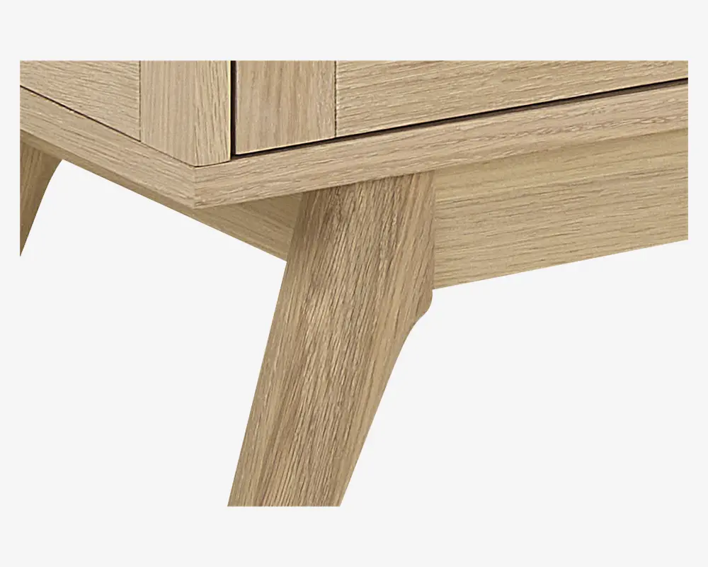 Nærbillede af et møbel med lys egetræsfinish og en glat, naturlig træstruktur. Billedet fremhæver et skråt, tilspidset ben og en enkel, moderne kant, hvilket indikerer en solid konstruktion og minimalistisk design.