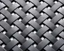 Nærbillede af et tæt vævet mønster lavet af flade, mat sorte strimler. Strimlerne er flettet sammen i et over-under kurveflet-design, hvilket skaber en tekstureret og holdbar overflade. Materialet virker robust, og vævningen er ensartet, hvilket giver både styrke og et moderne udtryk.