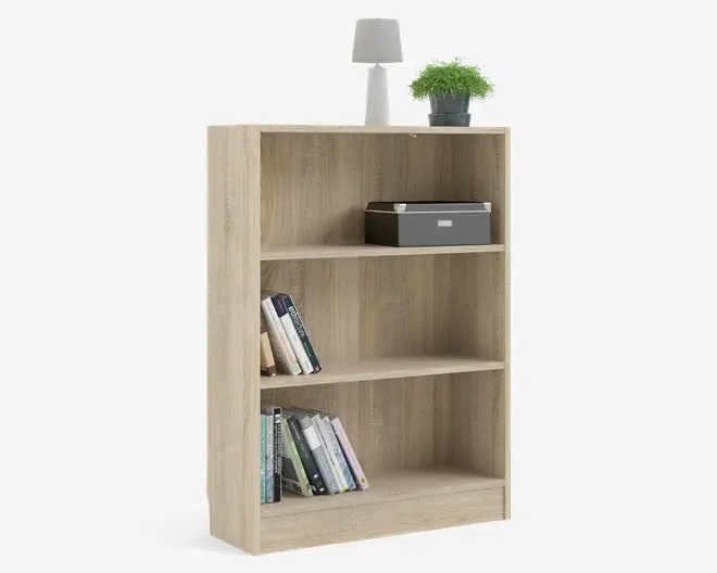 En reol med tre hylder i lyst egetræ-look og et enkelt, moderne design. Den øverste hylde har en grå opbevaringsboks, mens de nederste hylder viser et udvalg af bøger, der står både oprejst og skråt. Øverst på reolen står en lille bordlampe og en grøn potteplante, som giver et dekorativt præg til den funktionelle opbevaring.