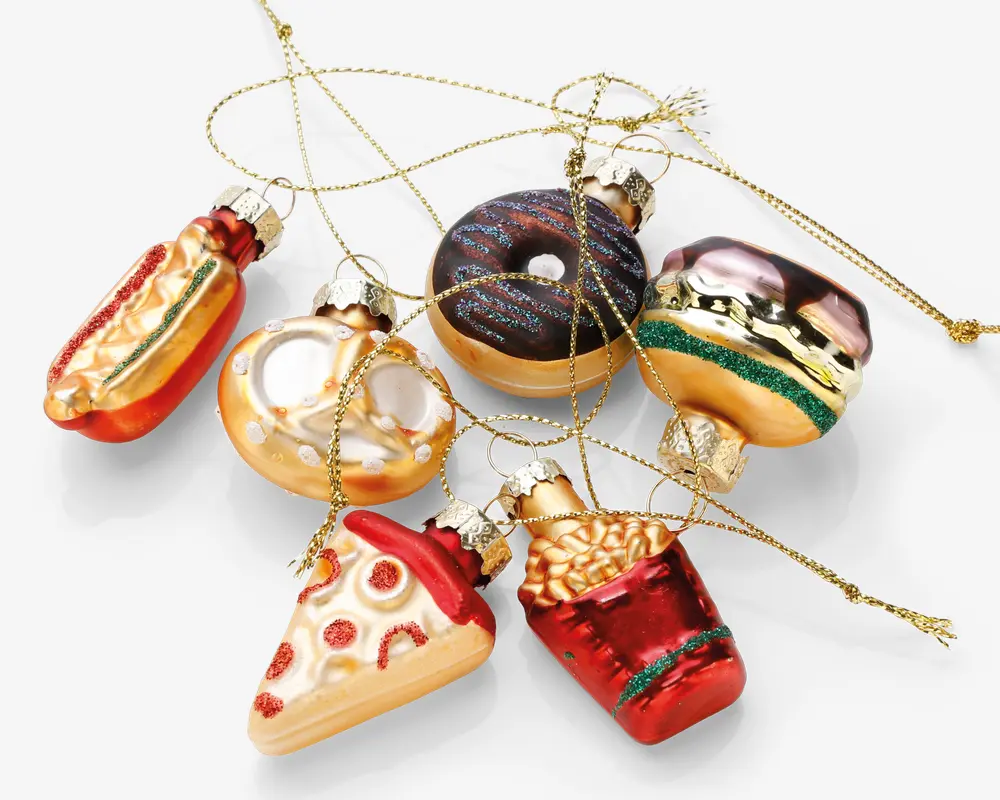 Et sæt med seks glasornamenter formet som populære fastfood-retter, herunder en hotdog, en pretzel, en chokoladedonut med krymmel, en hamburger med lag af bolle, salat og bøf, et stykke pepperonipizza og en rød karton med pommes frites. Hvert ornament har levende farver, metalliske detaljer og en gylden snor til ophæng, fastgjort til en sølvfarvet top.
