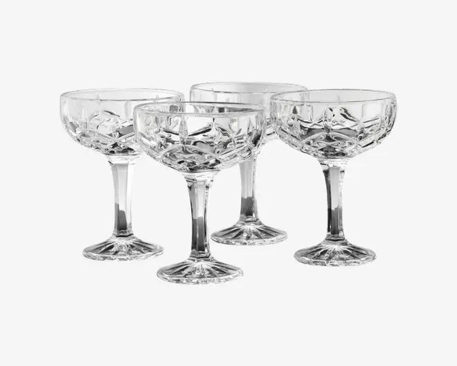 Sæt med fire klare glas med stilk, bred skål og indviklet geometrisk slibemønster. Glassene har en solid, facetteret fod og en kort stilk, hvilket giver dem et elegant og klassisk udseende. Det slebne design tilføjer tekstur og glans, hvilket gør dem velegnede til servering af cocktails eller mousserende drikke.