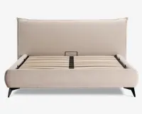 En moderne sengegavl med en høj, polstret hovedgavl i lysebeige stof. Rammen har rene, lige linjer og en blød, tekstureret overflade. Bunden består af jævnt fordelte lameller i træ til støtte af madrassen, og benene er skrå og mørke, hvilket giver et solidt fundament. Designet er minimalistisk og moderne, velegnet til forskellige soveværelsesstile.