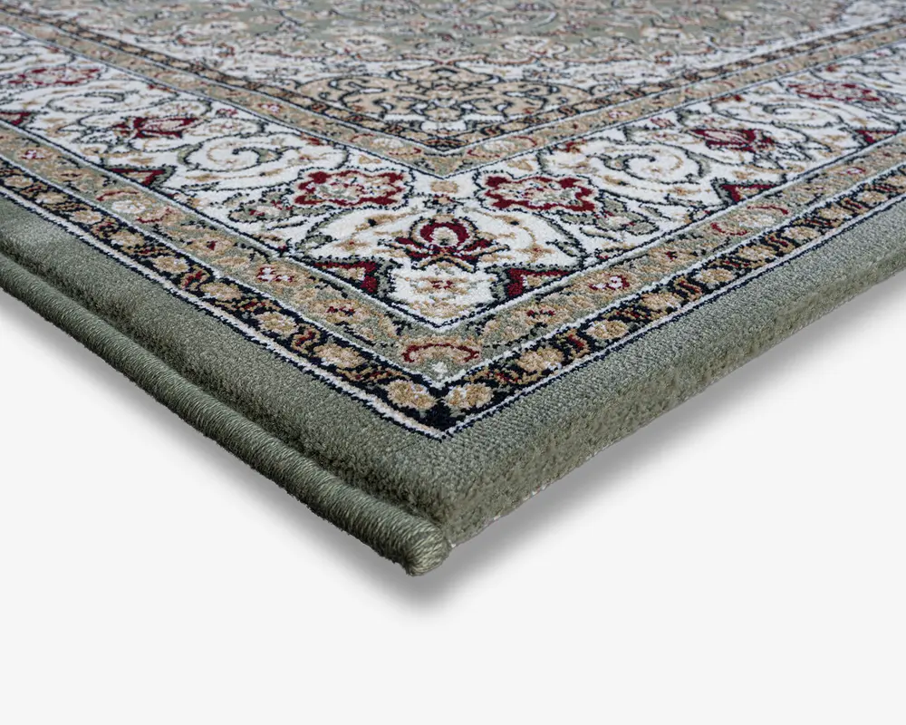 Nærbillede af et tæppehjørne, der viser en tyk, blød luv og tæt indbundne kanter. Tæppet har et indviklet, traditionelt mønster med blomster- og geometriske motiver i nuancer af creme, rød, grøn og beige. Kanten er detaljeret med gentagne designs, og overfladen ser blød og tæt ud, hvilket indikerer holdbarhed og komfort.