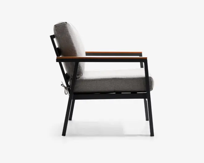 Sidevisning af en moderne stol med en robust sort metalramme, skrå ben og armlæn af træ. Sædet og ryglænet er polstret med lysegråt stof, hvilket giver et blødt og komfortabelt udtryk. Designet er minimalistisk med rene linjer, velegnet til moderne indretning.