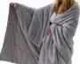 Et blødt, lysegråt tæppe med en glat, quiltet overflade. Tæppet er stort og omslutter personen, så det giver fuld dækning. Stoffet ser plysset og hyggeligt ud, perfekt til varme og afslapning. Kanterne er pænt afsluttede, og tæppet har en let glans, hvilket indikerer materiale af høj kvalitet.