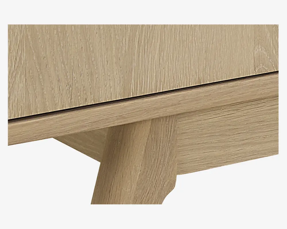 Nærbillede af en lys egetræsfinish med synlig træstruktur, der viser et robust, skråt ben og en glat, sømløs kant. Benet er kraftigt og let tilspidset, hvilket giver stabil støtte og et moderne udtryk.
