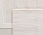 Nærbillede af to overlappende rektangulære tekstiler i en neutral offwhite farve. Det øverste tekstil har et fint, tæt vævet gittermønster med glat overflade og en pænt syet kant. Det nederste tekstil har et mere tekstureret, kurveflettet mønster med en let forhøjet kant, hvilket giver en diskret kontrast i struktur og udseende. Begge tekstiler har rene, færdige kanter og et minimalistisk, moderne udtryk.