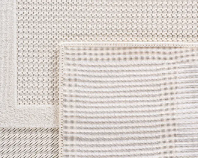 Nærbillede af to overlappende rektangulære tekstiler i en neutral offwhite farve. Det øverste tekstil har et fint, tæt vævet gittermønster med glat overflade og en pænt syet kant. Det nederste tekstil har et mere tekstureret, kurveflettet mønster med en let forhøjet kant, hvilket giver en diskret kontrast i struktur og udseende. Begge tekstiler har rene, færdige kanter og et minimalistisk, moderne udtryk.
