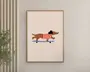 Minimalistisk illustration af en brun gravhund iført en rød- og hvidstribet sweater og sort beret, der kører på et blåt skateboard. Baggrunden er ensfarvet lysebeige, og kunstværket er indrammet i en enkel træramme.