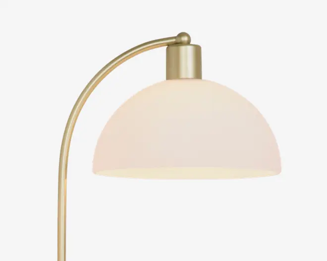 Lampe med en buet arm i børstet messing og en kuppelformet, mat hvid skærm. Designet er moderne og elegant med en glat finish og blødt, diffust lys.