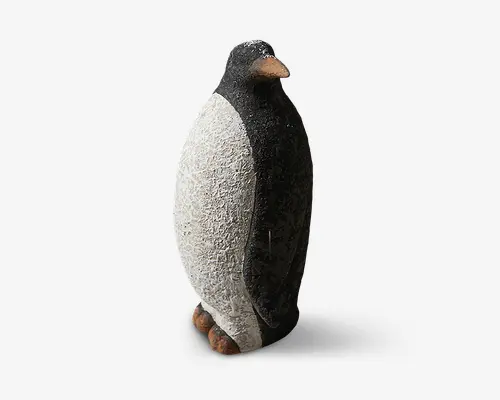 En dekorativ pingvinfigur med en tekstureret overflade. Kroppen er overvejende hvid med en ru, stenlignende finish, mens hovedet og ryggen er sorte med en glattere tekstur. Næb og fødder er malet i en naturlig brun-orange farve. Figuren står oprejst på en lille, flad base.