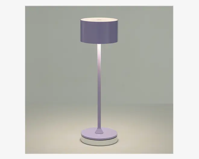Høj gulvlampe med en cylindrisk lampeskærm i en afdæmpet lavendelfarve. Lampen har en slank, lige stang og en rund, solid fod, som begge matcher skærmens farve. Designet er minimalistisk og moderne, og lampen udsender et blødt, diffust lys fra toppen og bunden af skærmen.